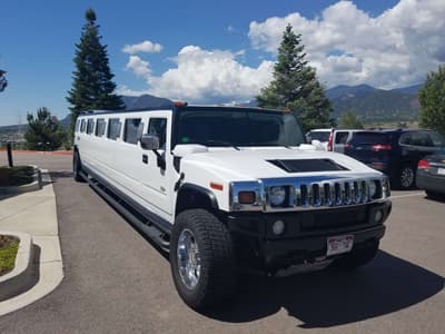 Avi Limo white stretch limousine parked with the Colorado mountains behind it